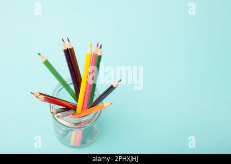 Multi-colored pencils in a glass jar on a blue background. Copy space Stock Photo