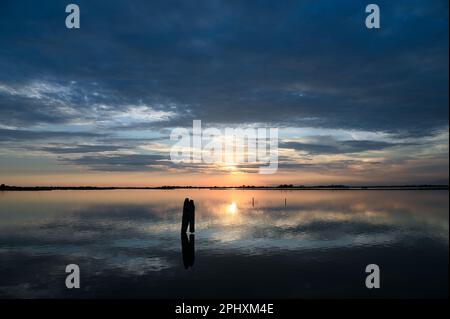 Picturesque view of calm sea water reflecting cloudy sky at sundown in peaceful evening Stock Photo