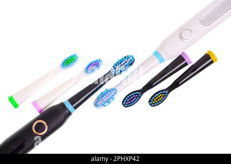 Black and white electric toothbrushes, accompanied by a set of color matching brush heads, all placed on a plain white background. Dental care and per Stock Photo