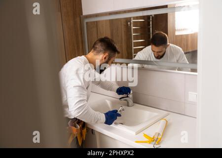 a worker installs a wash basin in a bathroom. Stock Photo