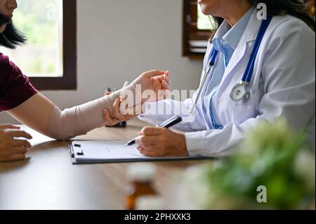 Close-up image of a professional senior Asian female orthopedic doctor checking her patient's wrist joint. Medical and health care concept Stock Photo