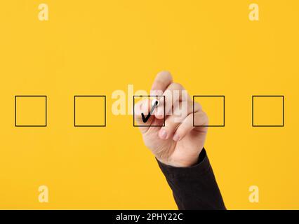 Approval and confirmation. Selecting the right option or making the correct decision. Male hand draws a check mark or tick in the middle of checkboxes Stock Photo