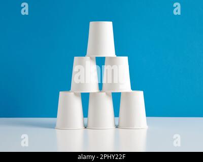 Pyramid of white paper cups on blue background. Stock Photo