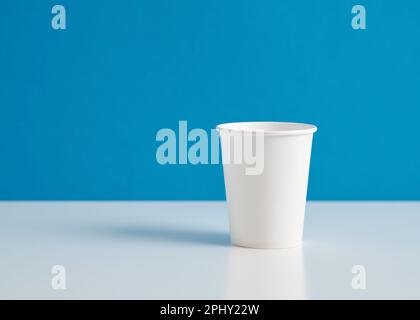 White paper cup on blue background. Stock Photo