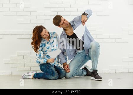 Smiling husband and wife sit taking care of utility bills and house maintenance documents, happy young couple read paperwork Stock Photo