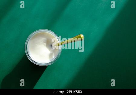 natural yoghurt in plastic container on green background Stock Photo