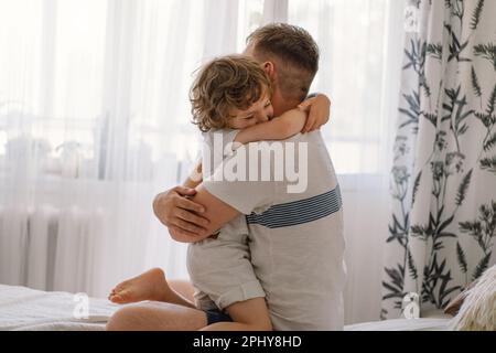 Father and his son are playing and hugging at home. Stock Photo