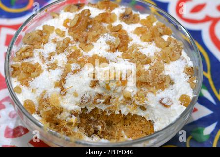Konafa topped with whipped cream, raisins, walnuts, shredded coconut and stuffed with cream and fresh mango layer and soaked with honey sugar syrup, E Stock Photo