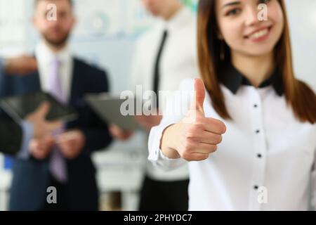 Businessman holds thumbs up in background are business partners Stock Photo