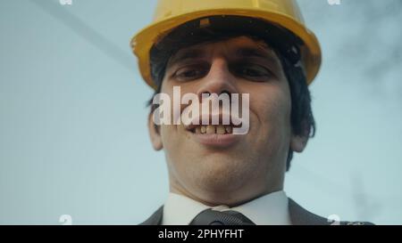 Young Construction Engineer or Contractor in a Suit Messaging or Using an App on His Smartphone Outdoors Stock Photo
