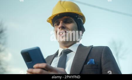 Modern Business and Shopping: A Young Entrepreneur or Civil Engineer Using a Smartphone for Online Purchases Stock Photo