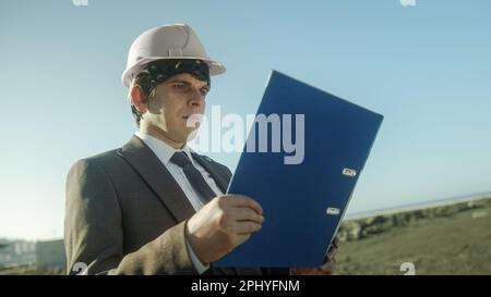 Civil Engineer Holding Blue Folder in Workplace Stock Photo