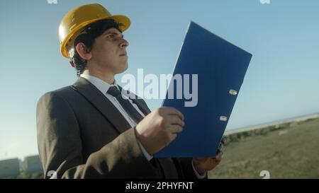 Businessman or Engineer Holding Blue Folder in Workplace Stock Photo