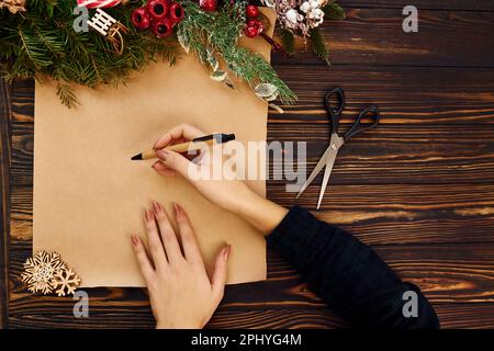 Woman writes on paper. Top view of christmas festive texture with new year decorations Stock Photo