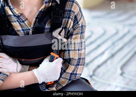 The master, dressed in overalls and a shirt, holding a wrench in his hand. Maintenance. construction concept. Stock Photo