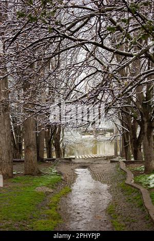 waterway with first melting snow in snowy city park on cold winter day Stock Photo