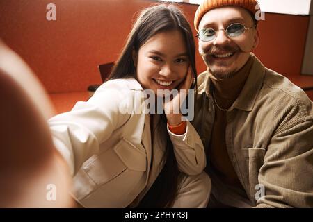 Cheerful woman and man taking selfie indoors Stock Photo