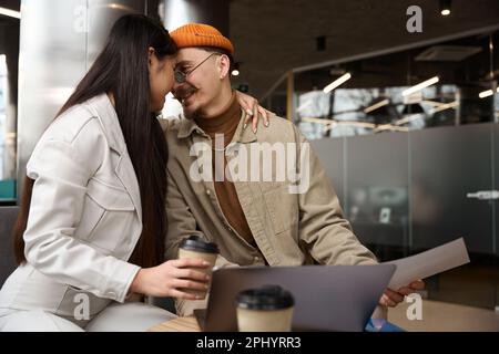 Romantic female office worker hugging her coworker at desk Stock Photo