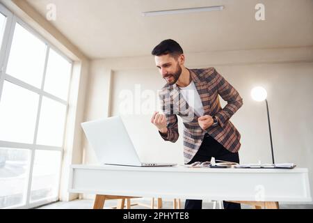 Works in the office. Young stylish businessman in suit indoors. Conception of success Stock Photo