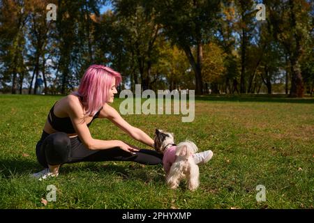 Smiling sportswoman performing leg stretch in public park Stock Photo