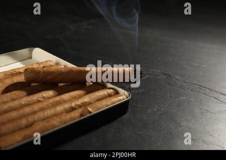 Many cigars in box on black table, closeup Stock Photo