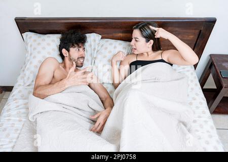 Upset couple lying in bed arguing. Top view of young couple lying in bed arguing. Marriage problems concept Stock Photo