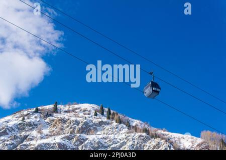 Almaty, Kazakhstan - January 08, 2023: cable car for skiers against the backdrop of a blue sky and snowy mountain slopes, view from the bottom up Stock Photo