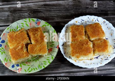 A traditional middle eastern dessert Knafeh Konafa made with spun pastry kataifi, soaked in a sweet sugar honey syrup, layered with cheese, clotted or Stock Photo