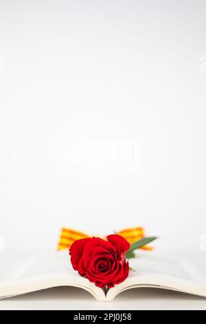 Close up red rose and ear of wheat in an opened book for Diada de Sant Jordi. Tradition of St Jordi Day in Catalonia. Catalan book and rose flower day Stock Photo