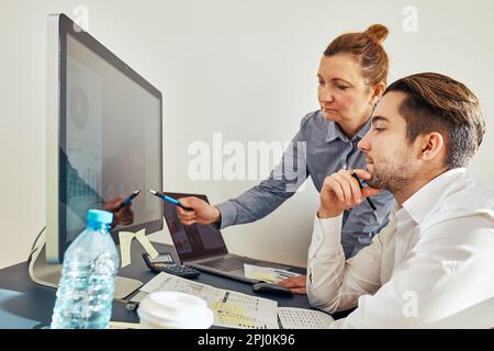 Business colleagues discussing financial data working together in office. People entrepreneurs working with charts and tables on computer. Two people Stock Photo