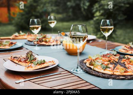Dinner in a home garden. Pizza, salads, fruits and white wine on table in a orchard in a backyard Stock Photo