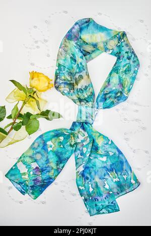 Silk colourful hand painted tied scarf put on white background. Woman fashion, tying a scarf, wearing a scarves. Stylish ways to tie and wear scarves Stock Photo