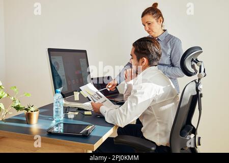 Two business people discussing financial data on computer. Businesswoman working with male colleague in office. People entrepreneurs working with char Stock Photo