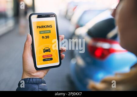 Woman using mobile parking app on smartphone. Driver using smartphone to pay for parking. Car park application on mobile phone. Convienience paying fo Stock Photo