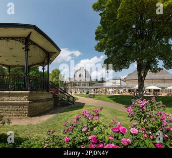 The bandstand, octagon and buildings of the Pavilion Gardens in the Spa Town of Buxton, Derbyshire. A summer day with roses in a Victorian public park Stock Photo