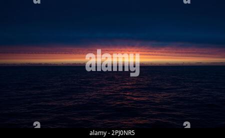 Last light on the ocean, from a ship as we crossed the North Sea, the sky lit red after sunset, reflecting in the dark waves as night arrives Stock Photo