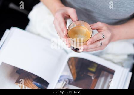 Closeup of woman reading magazine whilst drinking coffee Stock Photo