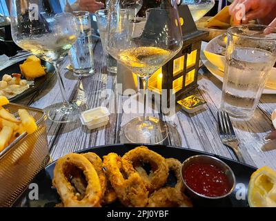 A Table at a restaurant, during a meal. food on the table, water and wine glasses, hands of people eating. Stock Photo