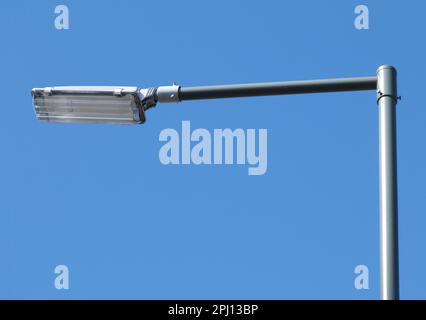 modern street lamp with square head under blue sky in perspective view on pewter color tubular light pole. blue sky background. lighting technology Stock Photo