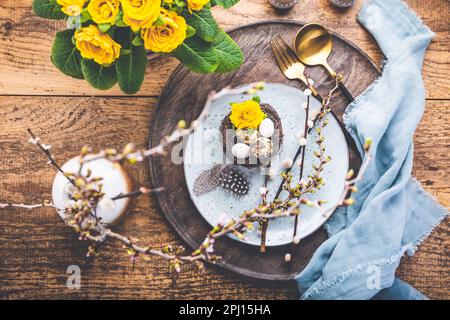 Easter table setting with spring flowers and cutlery on wooden table.  Spring Easter Holiday Table Stock Photo