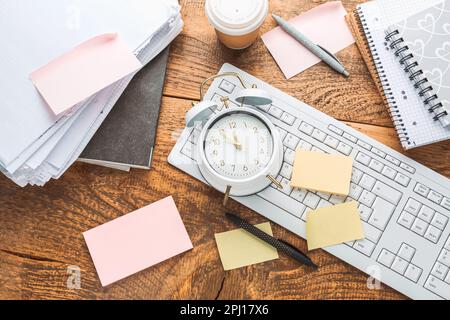 Time management concept. Composition with alarm clock on wooden table with laptop computer, stationary and post-it notes Stock Photo