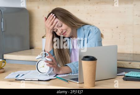 Despaired woman sitting at desk in office surrounded by paperwork, Work Life balance, work lif balance concept Stock Photo