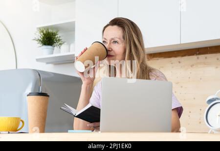 A thoughtful woman drinking a lot of coffee while doing creative work Stock Photo