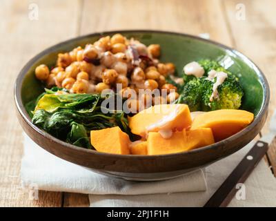 Broccoli Buddha bowl with sweet potato, spinach, spiced chickpeas and a tahini sauce Stock Photo