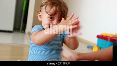 Successful baby clapping hands. One year old infant child solving puzzle Stock Photo