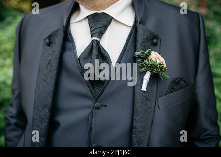 A smartly dressed person at wedding wearing a suit and a coordinating tie with flowers in a pocket Stock Photo