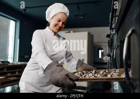 Happy smiling baker holding tray with cooked oatmeal cookies Stock Photo