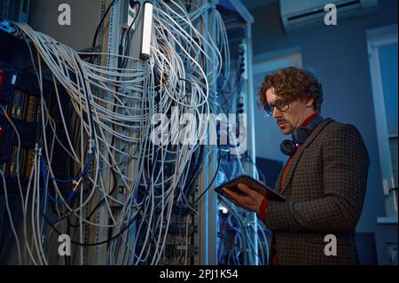 Male IT technical specialist makes a diagnosis in server room Stock Photo