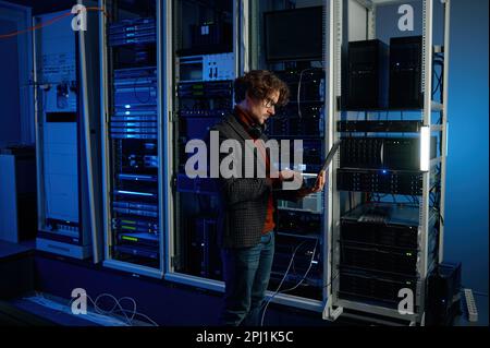 IT technician using digital tablet while working in data center with server rack Stock Photo