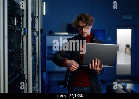 IT technician switching wire to laptop computer Stock Photo